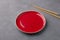 Red vintage ceramic plate and chopsticks on gray background