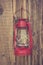 Red vintage handle gas lantern on rustic wooden wall.