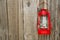 Red vintage handle gas lantern on rustic wooden wall.