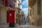 Red vintage old fashioned mail box on narrow street with stairs in Valetta, Malta