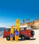 Red Vintage, Retro, Old-fashioned mini bus van camper VW T2 with surfboard on beach, cliff, palm tree