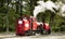 Red vintage steam locomotive moving along railroad tracks