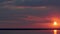 Red-violet sunset with light clouds lit by the rays of the sun and floating water