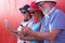 Red wall on background for a group of three caucasian people with colored hats,bow ties and suspenders. Enjoying a funny day of