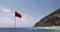 Red warning flag on the beach blue sea, sky and land in the background â€“ Wind and Sea Summer Video