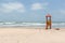 Red watchtower with a yellow ladder at the beach with the sea in the background in the Gambia