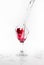 Red water spill from a broken wine glass on white background