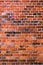 Red weathered old brick wall background, vertical texture. Grunge masonry, exposed vintage building facade.