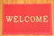 Red welcome carpet on wooden background