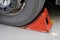 Red wheel chock under the wheel of a car close-up.