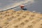 Red wheelbarrow with one wheel on the pavement and many small slides of sand on the ground.