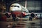 A red and white aircraft is parked in a hangar, awaiting service