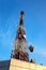 Red and white antenna (cellular tower) under blue sky.