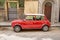 Red and white automobile parked in front of an iconic Italian building