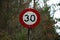 Red white and black 30 miles kilometers per hour speed limit sign hit gun shots in Riverhead Forest, Kumeu, Auckland, New Zealand