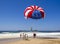 Red, white and blue of American flag parasail against bright blue sky.
