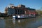 Red white and blue barge passes along river Avon in front of the RSC