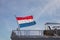 A red-white-blue Netherlands national flag flutters in the wind on the side of an army warship