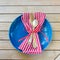 Red White and Blue Picnic Table Place Setting with napkin, fork, spoon and plate. Square and flat layout style photo taken outsid