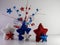 Red, white and blue tinsel and glitter stars standing on a white counter with a decorative spray of curled ribbon and stars behind