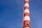 Red and white brick industrial pipe against the blue sky.6