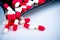 Red-white capsule pills on drug tray and some on white table. Pharmacy drugstore background. Pharmaceutics concept. Pharmaceutical