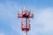 Red and white cellular tower with aerials on blue