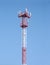 Red and white cellular tower with aerials on sky