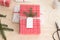 Red and white christmas gifts surrounded with pine cones, leaves and twine on a wooden table