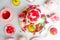 Red and white confection berry, fruit jelly desserts on cake stand, teapot on white table in candy shop or restaurant