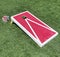 Red and white cornhole game on a green field