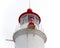 Red and white cylindrical stone tower of a lighthouse with lantern and gallery