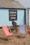 Red and white deckchairs sitting on shingle beach with a Fresh fish sign