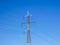 Red white electricity pylon against blue sky