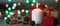 Red and white festive candles burn with a yellow flame on a table among gifts in craft paper, rattan balls, cinnamon sticks and