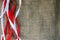 Red and white festive ribbons, threads against the texture of brown old linen cloth, linen natural material with a coarse perpendi