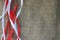 Red and white festive ribbons, threads against the texture of brown old linen cloth, linen natural material with a coarse perpendi