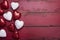 Red and white glitter hearts on a red wooden background