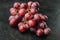 Red and white grapes, dark red fruits, on black stone background