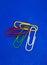 A red white green and yellow paperclip with a blue background