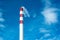 Red and white industrial chimney standing out in the cloudy sky