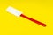 Red and white kitchen spatula made of silicone and plastic insulated on a yellow surface