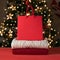 Red and white knitted sweaters stack on red table, sparkling shopping bag mockup with empty copy space, blurred