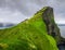 Red and white Kullur lighthouse on the stunning green cliffside of the Faroe Islands