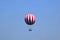 Red and white large balloon levitating with passengers high up