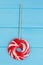 Red and white large spiral lollipop on stick.