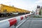 Red and white level crossing railway barrier which block the road and locomotive of empty freight train.