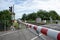 Red and white level crossing railway barrier which block the road and regional train move on the railway.