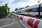 Red and white level crossing railway barrier which block the road and regional train move on the railway.