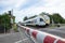 Red and white level crossing railway barrier which block the road and regional train move on the railway.